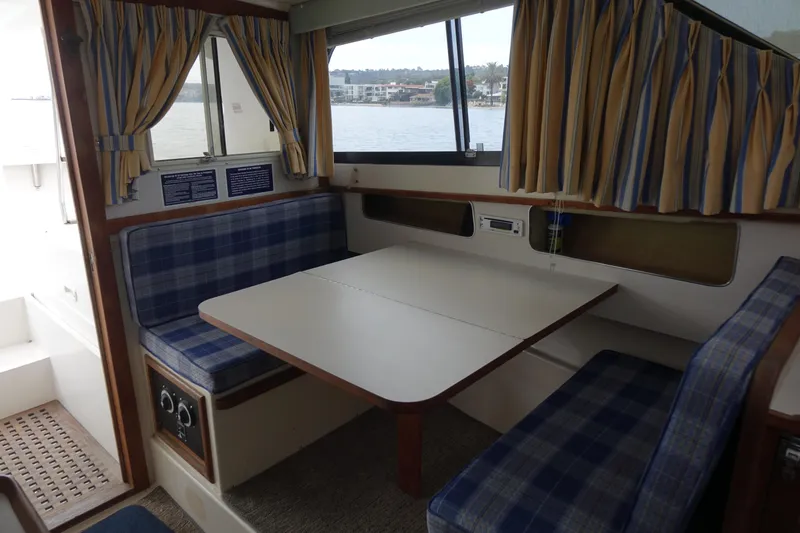 Slide: The Image of 1988 Blackfin 29 Flybridge interior with plaid seating and dining table. - 36