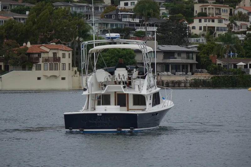 Slide: The Image of 1988 Blackfin 29 Flybridge boat on calm water near residential shoreline. - 4