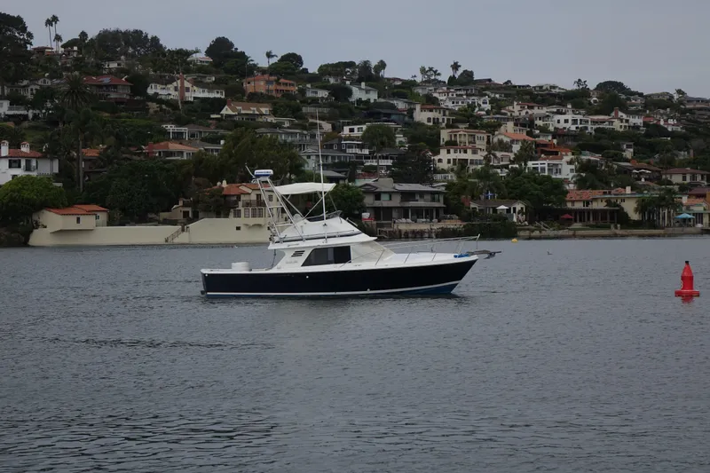 Slide: The Image of 1988 Blackfin 29 Flybridge boat on calm water near coastal homes. - 5