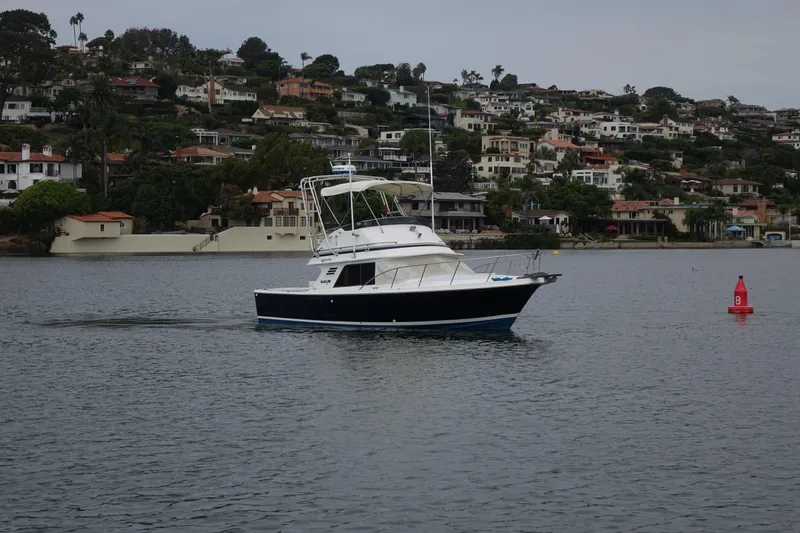 Slide: The Image of 1988 Blackfin 29 Flybridge boat cruising near coastal homes. - 6
