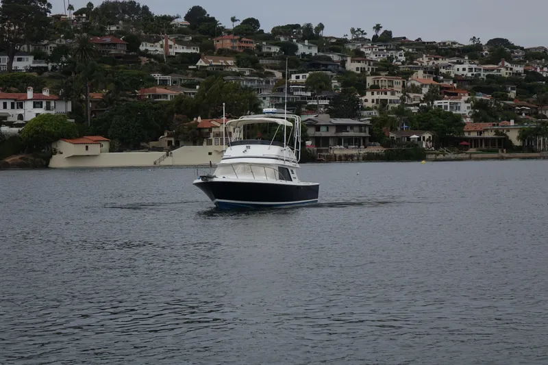 Slide: The Image of 1988 Blackfin 29 Flybridge boat cruising on a calm lake with houses in the background. - 9