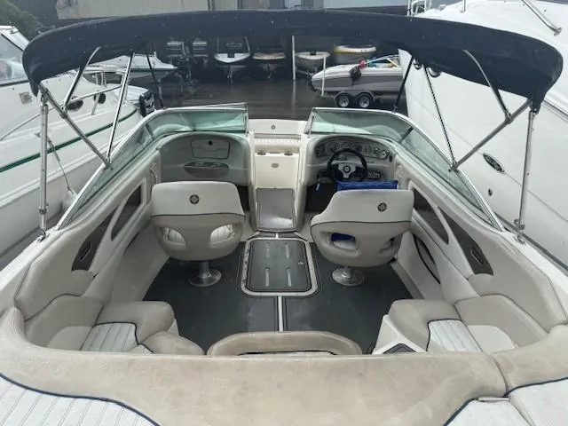 Slide: The Image of 2006 Bryant 219 boat interior with seating, steering wheel, and canopy in a marina setting. - 18