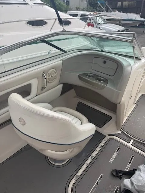 Slide: The Image of 2006 Bryant 219 boat interior with white seating and dashboard, docked near other boats. - 9