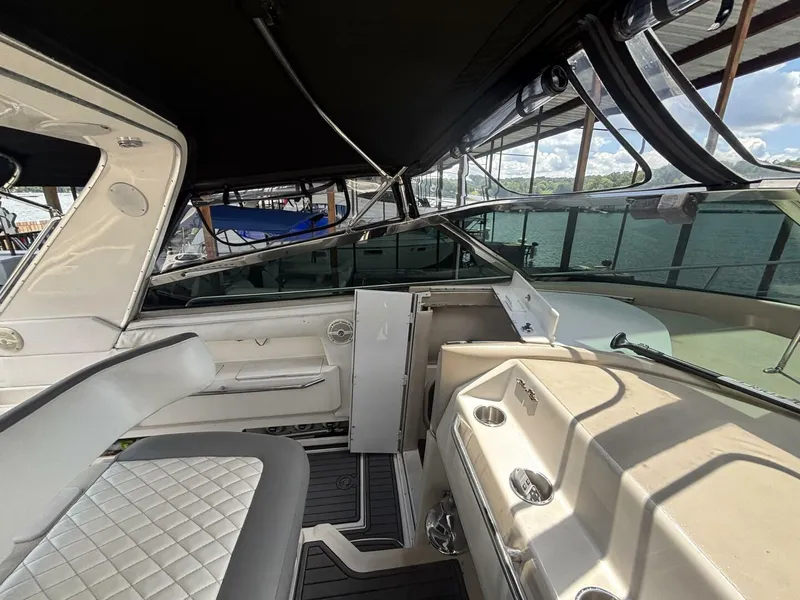 Slide: The Image of 1996 Sea Ray 500 Sundancer interior with seating and helm, docked by the water. - 4
