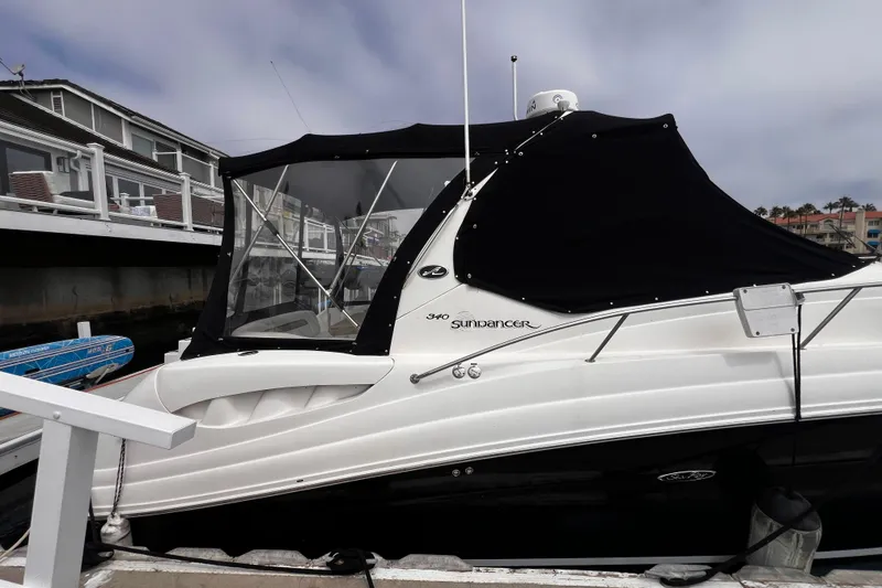 Slide: The Image of 2007 Sea Ray 340 Sundancer docked, featuring a black canopy and sleek white hull. - 12