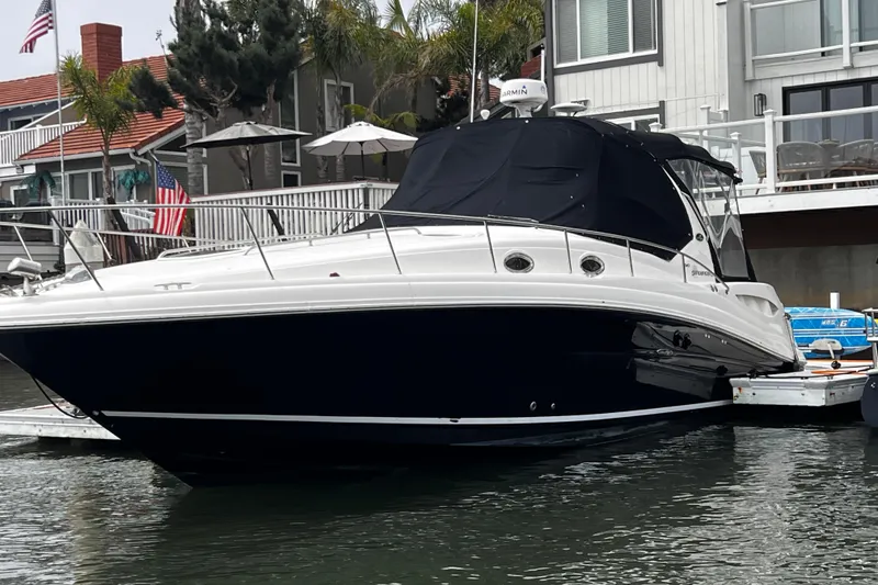 Slide: The Image of 2007 Sea Ray 340 boat docked near waterfront homes, featuring sleek design and black canopy. - 14