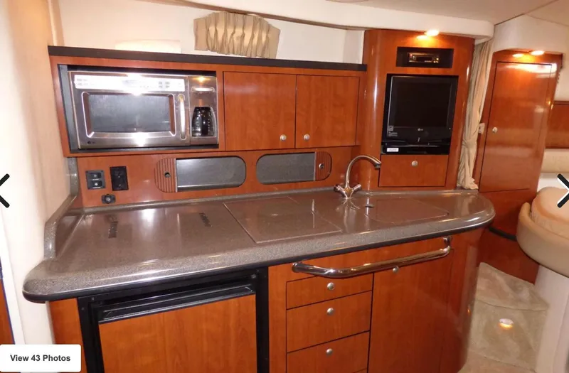 Slide: The Image of 2007 Sea Ray 340 yacht interior kitchen with microwave, sink, and wooden cabinetry. - 3