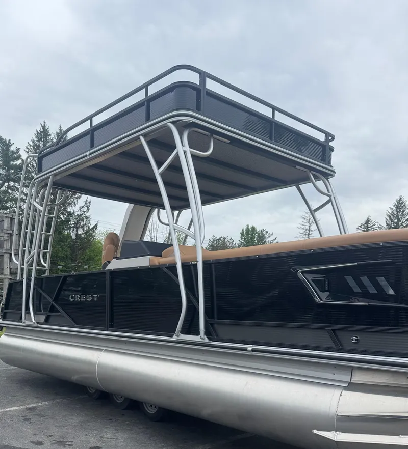 The Image of 2025 Crest Caribbean LX 250 pontoon boat with upper deck, parked outdoors. - 0