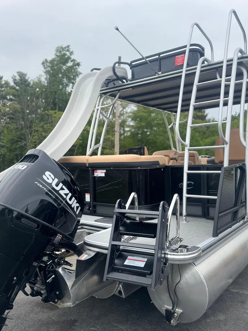 Slide: The Image of 2025 Crest Caribbean LX 250 pontoon boat with Suzuki engine and slide, docked outdoors. - 2