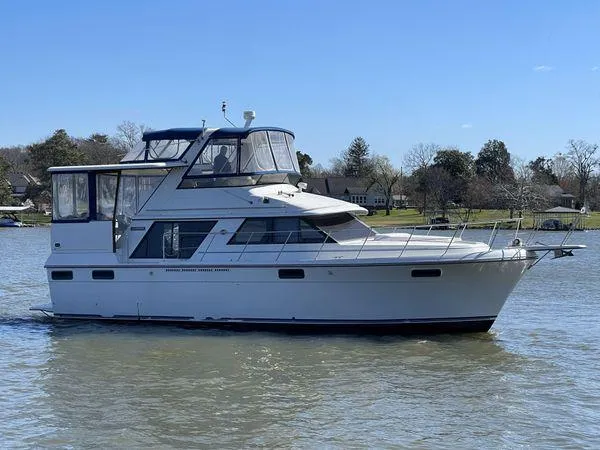 Slide: The Image of 1987 Carver 420 Cockpit Motor Yacht on a calm lake under clear blue skies. - 0