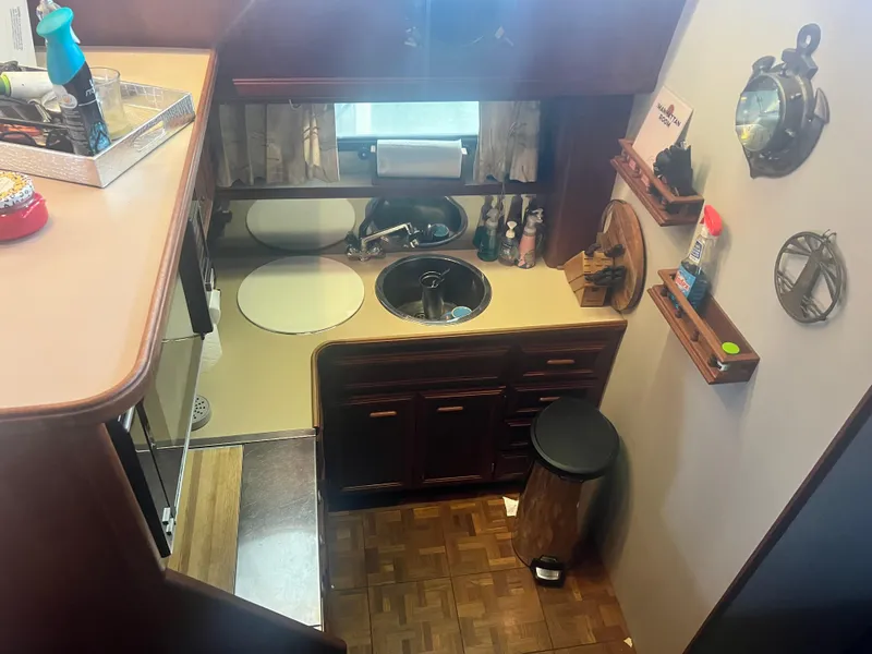 Slide: The Image of 1987 Carver 420 Cockpit Motor Yacht kitchen with sink, cabinets, and nautical decor. - 19