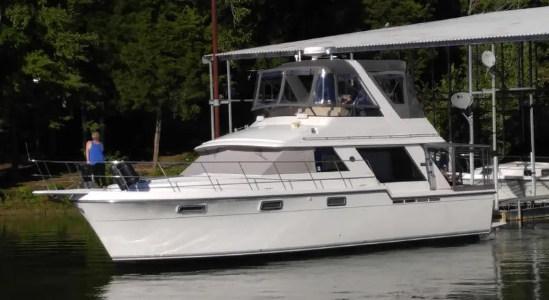 Slide: The Image of 1987 Carver 420 Cockpit Motor Yacht docked near lush greenery. - 2