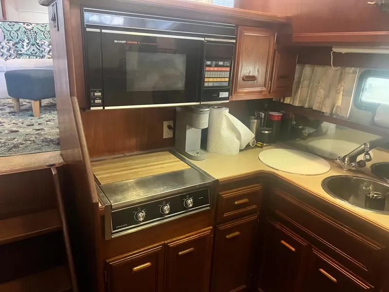 Slide: The Image of 1987 Carver 420 Cockpit Motor Yacht kitchen with microwave, stove, and sink. - 21