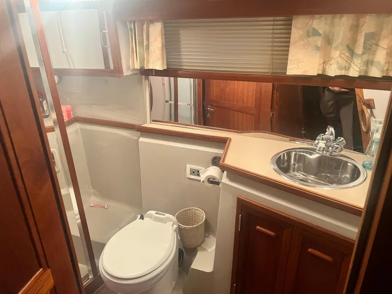 Slide: The Image of 1987 Carver 420 Cockpit Motor Yacht bathroom with sink, toilet, and wooden cabinetry. - 26