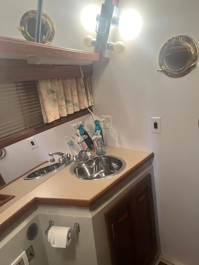 Slide: The Image of 1987 Carver 420 Cockpit Motor Yacht bathroom with sink, mirror, and porthole window. - 28
