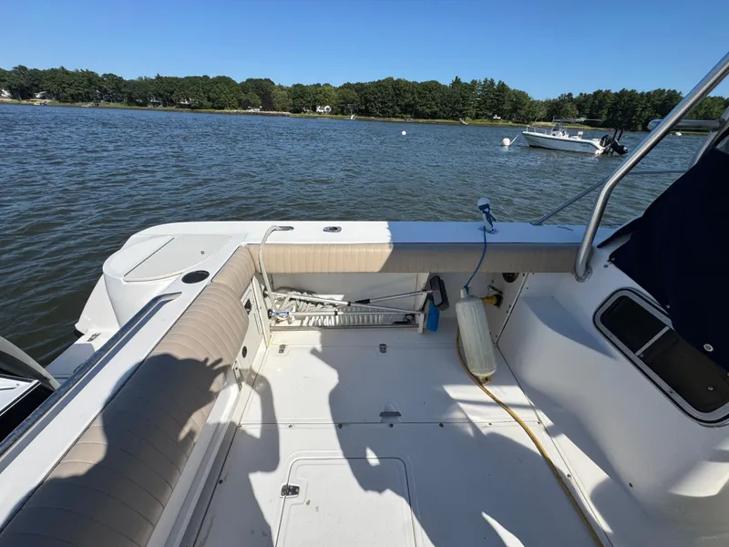 Slide: The Image of 1999 Boston Whaler 28 Conquest boat interior with seating, on a calm lake. - 10
