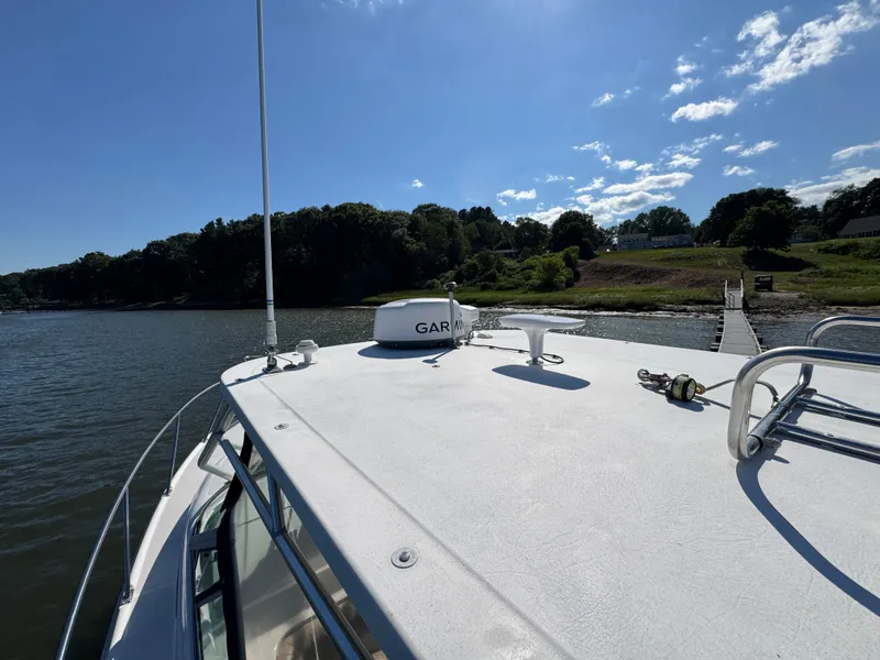 Slide: The Image of 1999 Boston Whaler 28 Conquest boat docked by a scenic shoreline. - 15