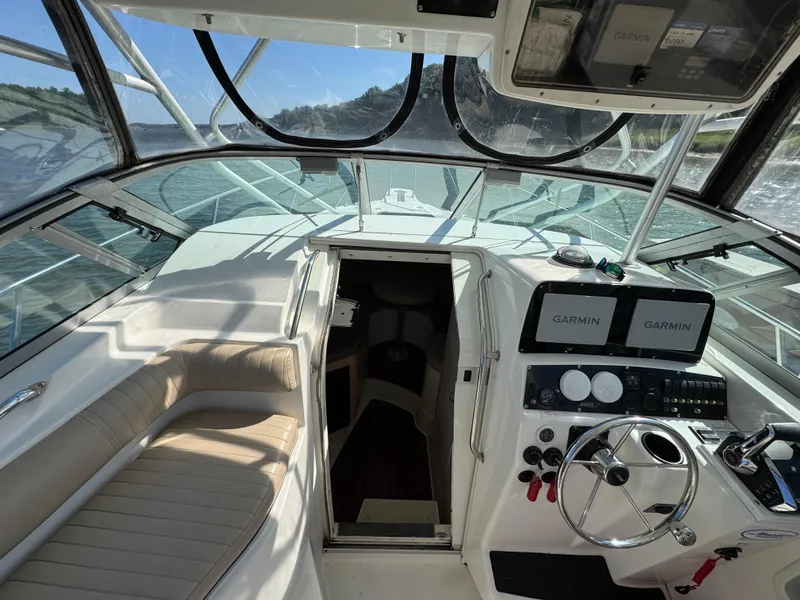 Slide: The Image of 1999 Boston Whaler 28 Conquest cockpit with Garmin navigation, steering wheel, and seating. - 22