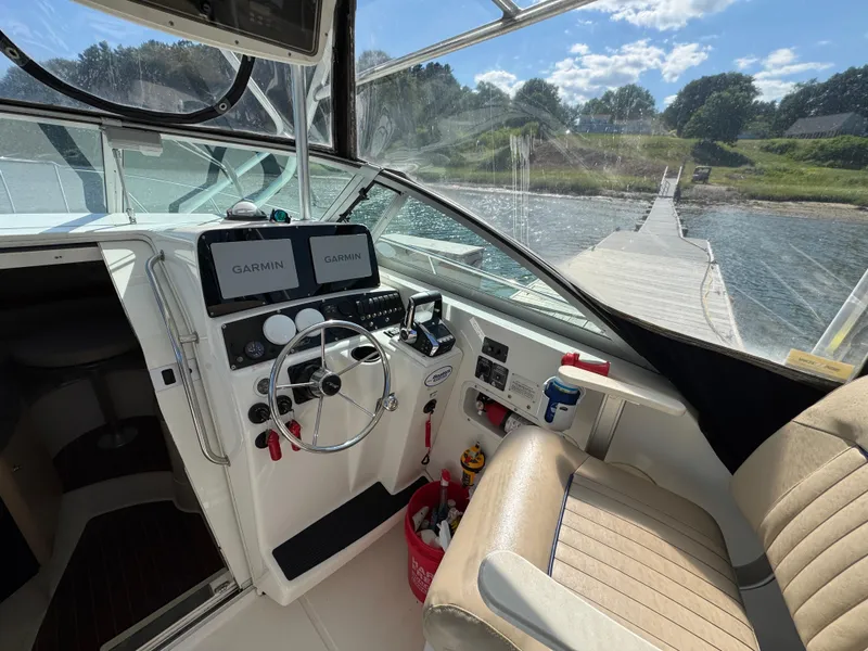 Slide: The Image of 1999 Boston Whaler 28 Conquest cockpit with Garmin navigation, docked by a scenic shoreline. - 24