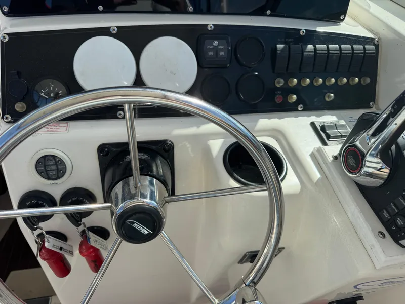 Slide: The Image of Control panel of a 1999 Boston Whaler 28 Conquest boat with steering wheel and switches. - 26