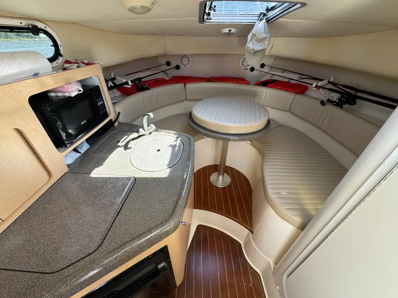 Slide: The Image of 1999 Boston Whaler 28 Conquest cabin interior with seating, table, and kitchenette. - 31