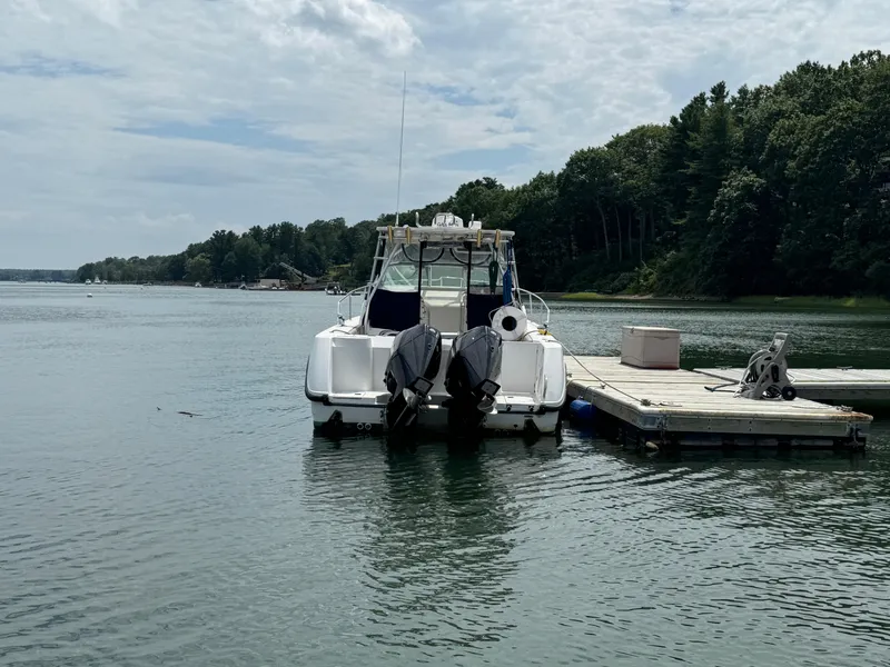 Slide: The Image of 1999 Boston Whaler 28 Conquest docked on a serene lake with lush trees. - 4