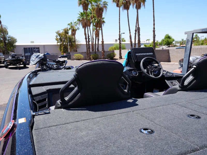 Slide: The Image of 2025 Skeeter ZXR20 boat interior with steering wheel and seats, parked outdoors under palm trees. - 11