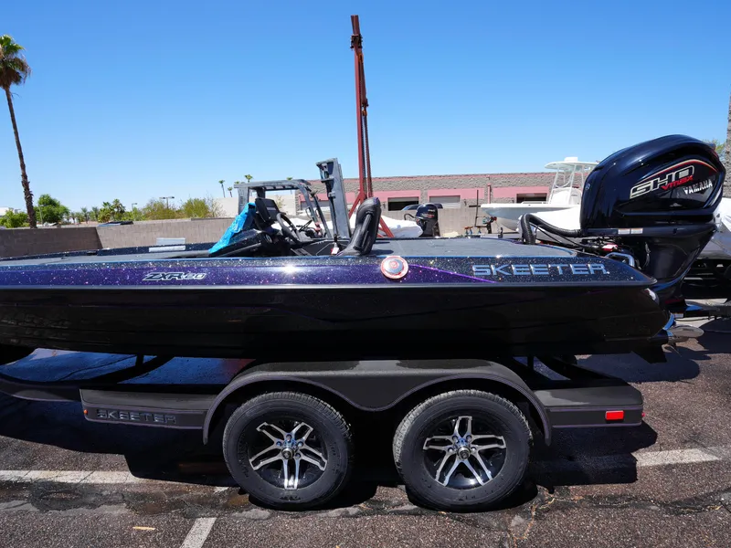 Slide: The Image of 2025 Skeeter ZXR20 boat on trailer, parked outdoors under clear blue sky. - 9