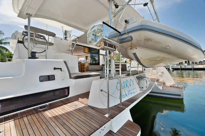 Slide: The Image of 2017 Lagoon 42 catamaran docked at a marina with palm trees and clear skies. - 13