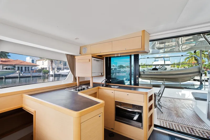 Slide: The Image of 2017 Lagoon 42 catamaran with dinghy, docked at marina, featuring spacious deck and seating area. - 18