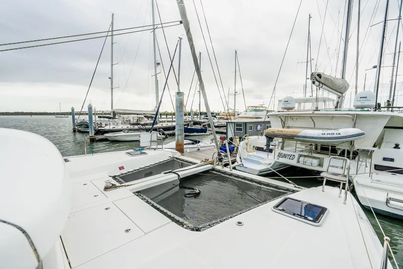 Slide: The Image of 2017 Lagoon 42 catamaran docked, showcasing sails and mast against a coastal backdrop. - 78