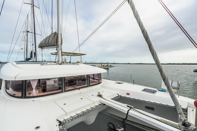 Slide: The Image of 2017 Lagoon 42 catamaran with logo and seating area, docked near waterfront homes. - 79
