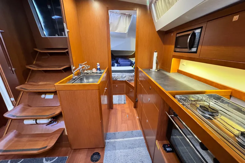 Slide: The Image of 2016 Beneteau Oceanis 48 yacht interior with modern kitchen and wooden cabinetry. - 22