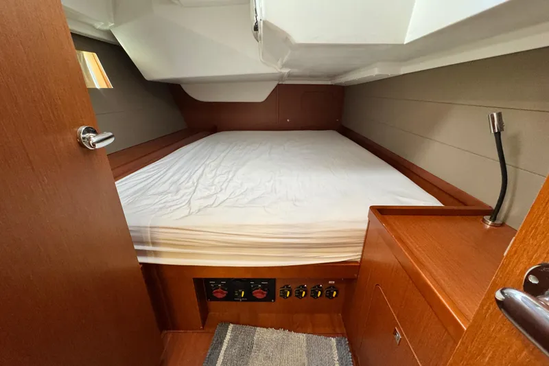 Slide: The Image of 2016 Beneteau Oceanis 48 cabin interior with bed, wooden finish, and reading light. - 25