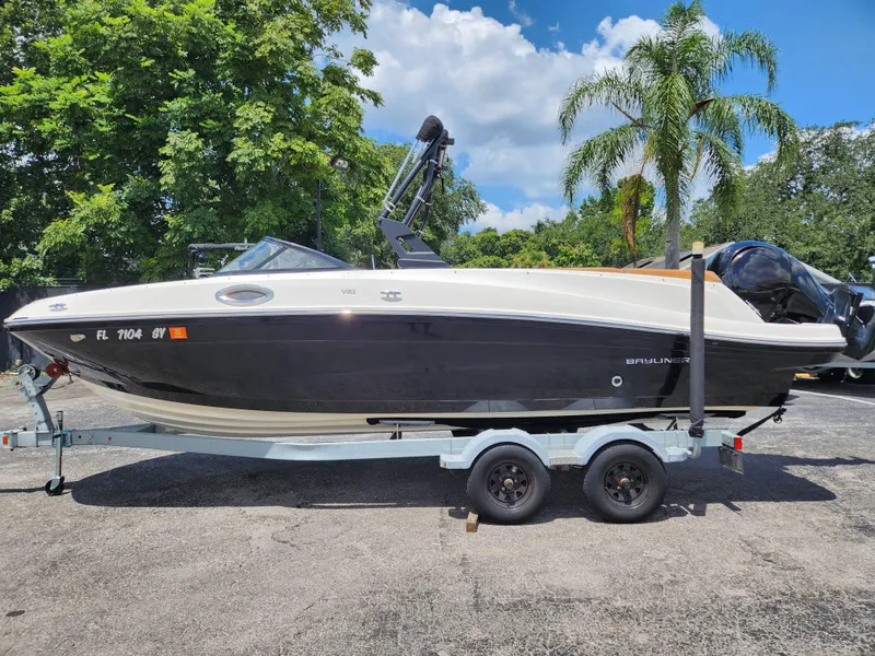 Slide: The Image of 2021 Bayliner VR6 Bowrider OB on trailer, parked outdoors with lush greenery background. - 1