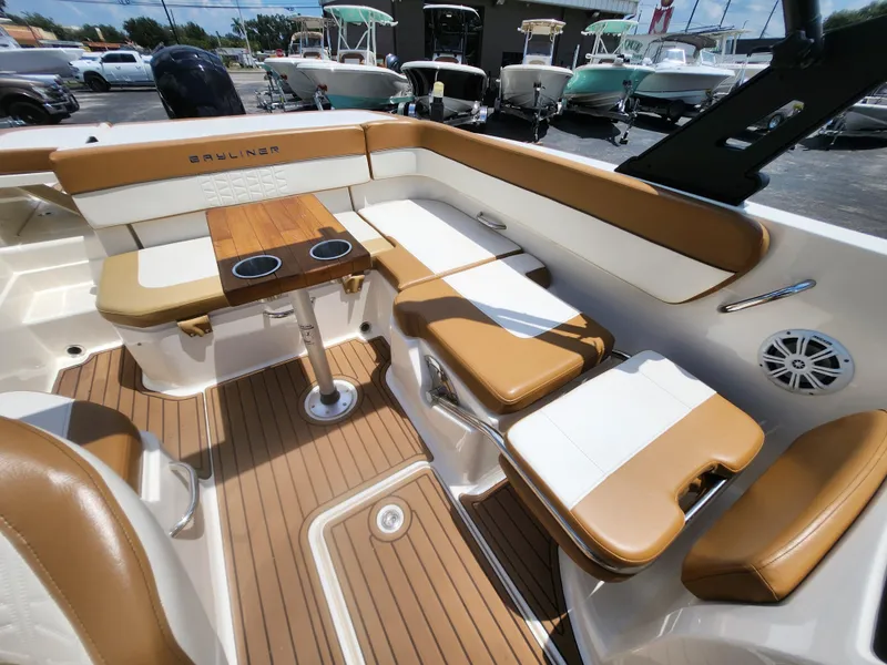 Slide: The Image of 2021 Bayliner VR6 Bowrider OB interior with tan seating, wooden table, and cup holders. - 9