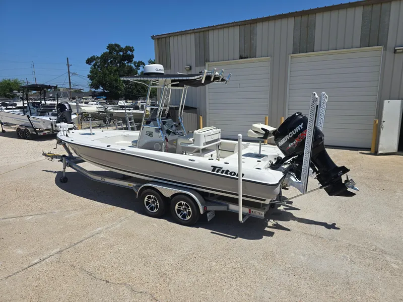 Slide: The Image of 2014 Triton 240 LTS Pro boat on trailer, parked outside a warehouse. - 2