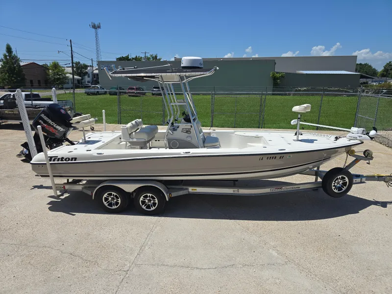 Slide: The Image of 2014 Triton 240 LTS Pro boat on trailer, parked outdoors under clear blue sky. - 5