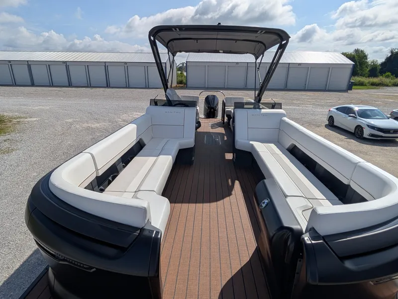 Slide: The Image of 2025 Manitou Explore boat with spacious seating and sleek design, parked outdoors. - 10