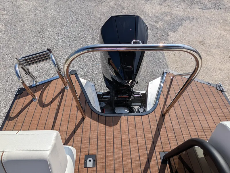 Slide: The Image of 2025 Manitou Explore boat deck with motor and ladder, featuring sleek design and wood finish. - 14