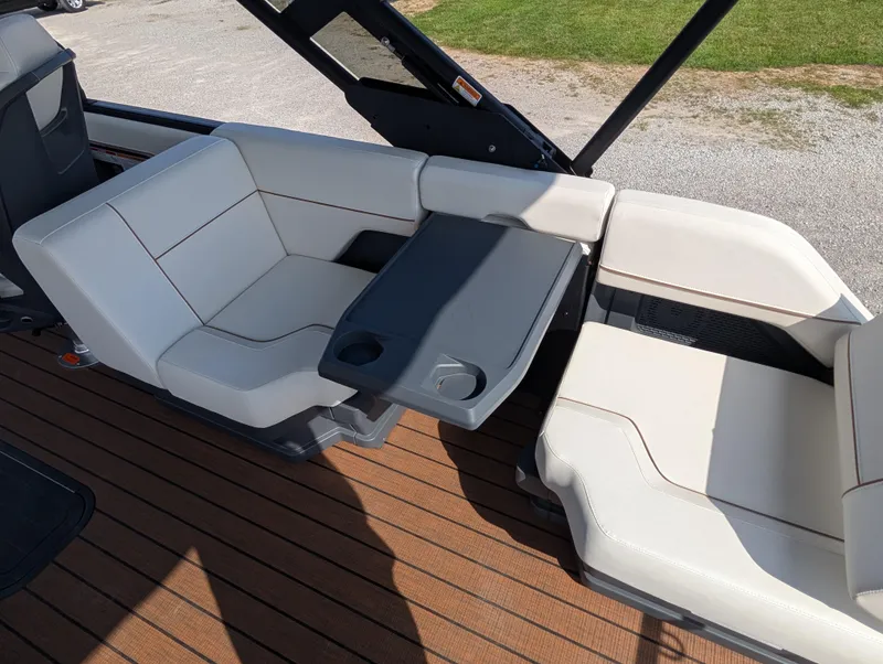 Slide: The Image of 2025 Manitou Explore boat interior with white seating and a gray table on wooden deck. - 17