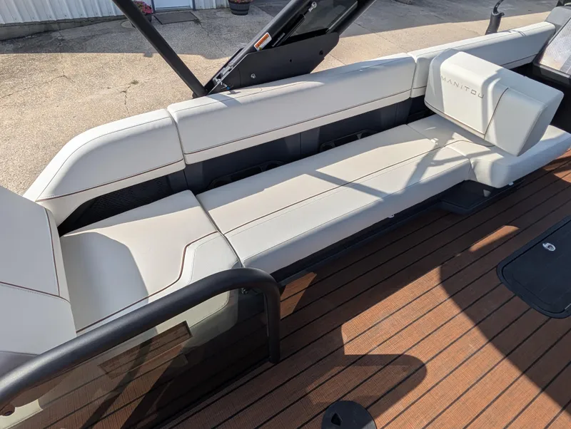 Slide: The Image of 2025 Manitou Explore boat interior with white seating and wooden deck. - 18