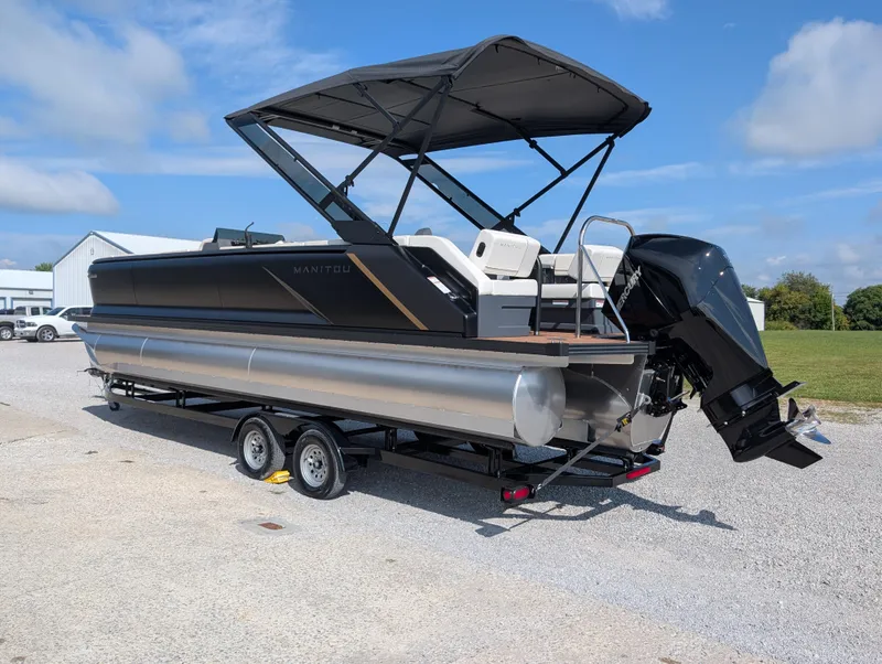 Slide: The Image of 2025 Manitou Explore pontoon boat with canopy and outboard motor on trailer. - 2