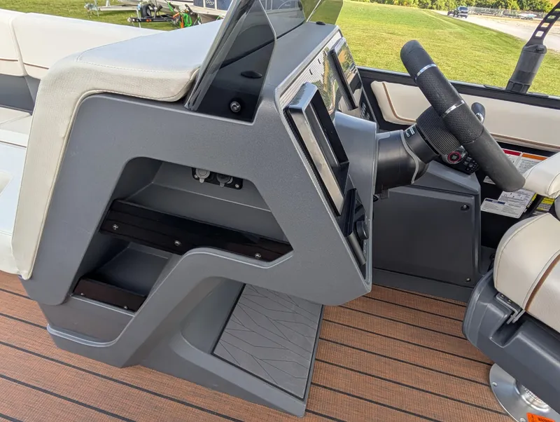 Slide: The Image of 2025 Manitou Explore boat dashboard with steering wheel and seating. - 25