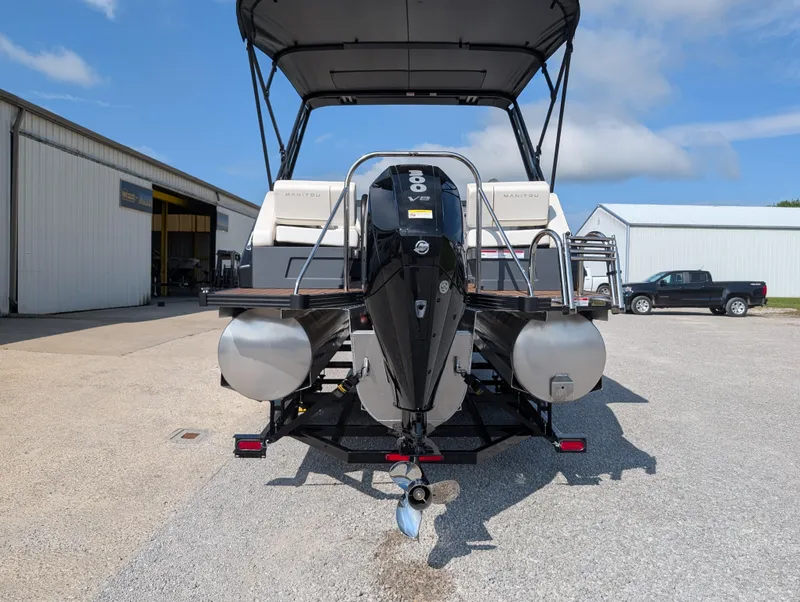 Slide: The Image of 2025 Manitou Explore pontoon boat with powerful outboard motor, parked outdoors. - 5