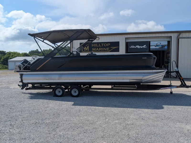 Slide: The Image of 2025 Manitou Explore pontoon boat on trailer at Hilltop Marine dealership. - 6