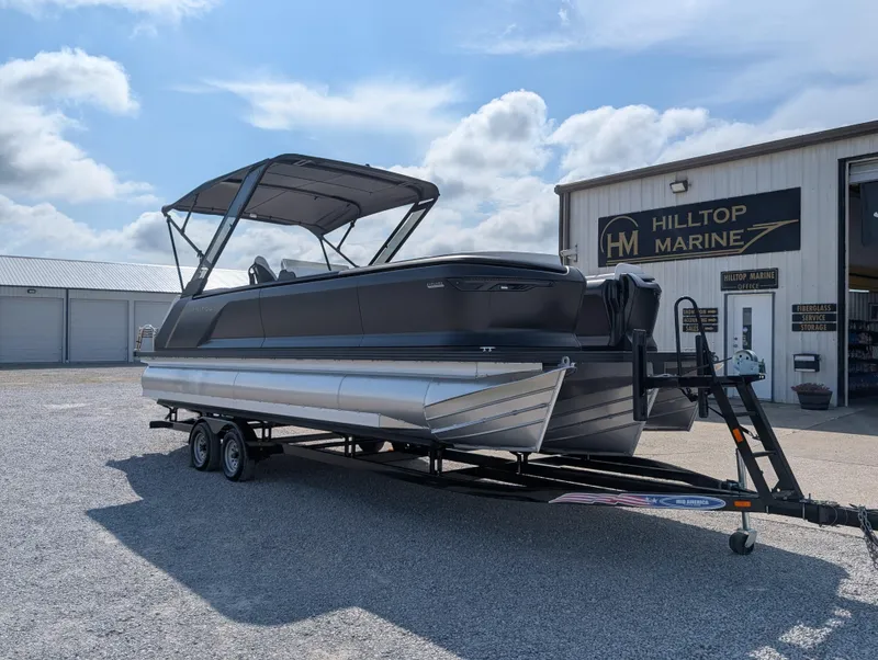 Slide: The Image of 2025 Manitou Explore pontoon boat on trailer at Hilltop Marine dealership. - 7