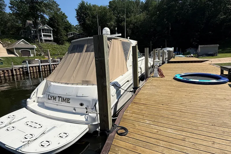Slide: The Image of 1998 Sea Ray 540 Sundancer docked at a wooden pier, surrounded by lush greenery. - 10