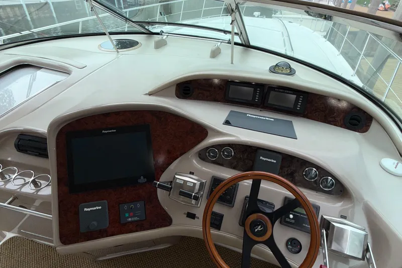 Slide: The Image of 1998 Sea Ray 540 Sundancer helm with navigation controls and wood-accented steering wheel. - 13