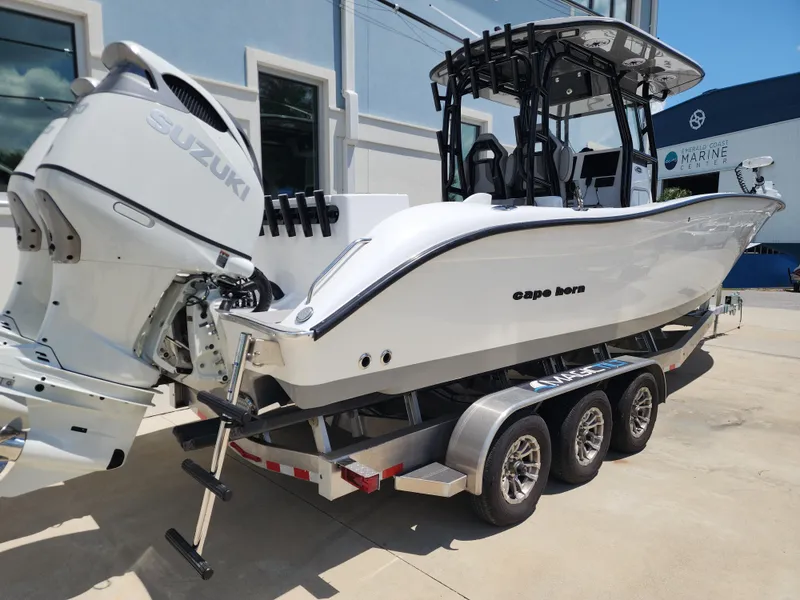Slide: The Image of 2025 Cape Horn 32 XS boat on trailer with Suzuki engine, parked outside marine center. - 6